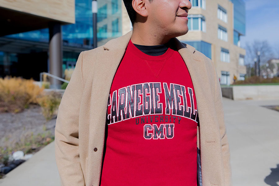 Man standing on campus, with a focus on his Carnegie Mellon shirt