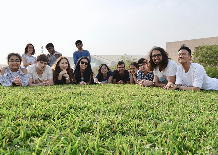 Photo of a group of students laying in the grass and smiling