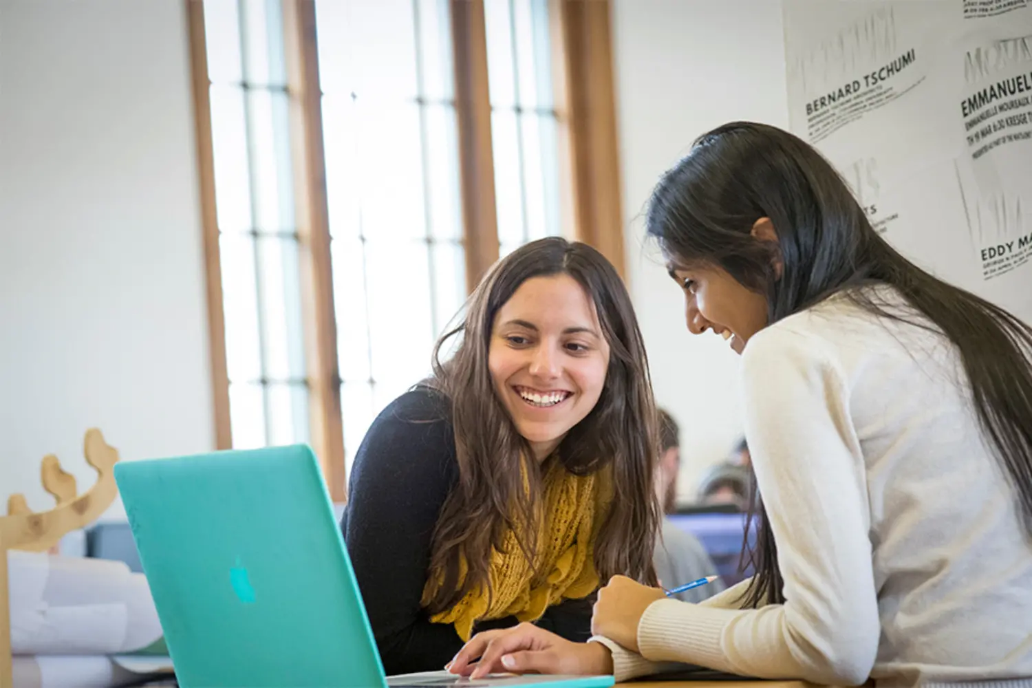 Two students, working together at a laptop,