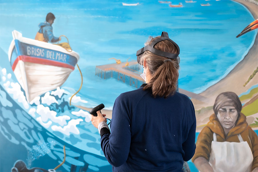 Genevieve Tremblay, with an AR headset, in front of a sea mural.