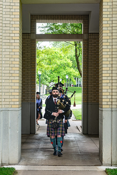 A bagpiper leads the 2024 PBK inductees in a procession through the CFA walkway.