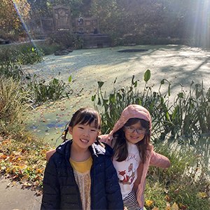 Students stand in front of a pond in Schenley Park