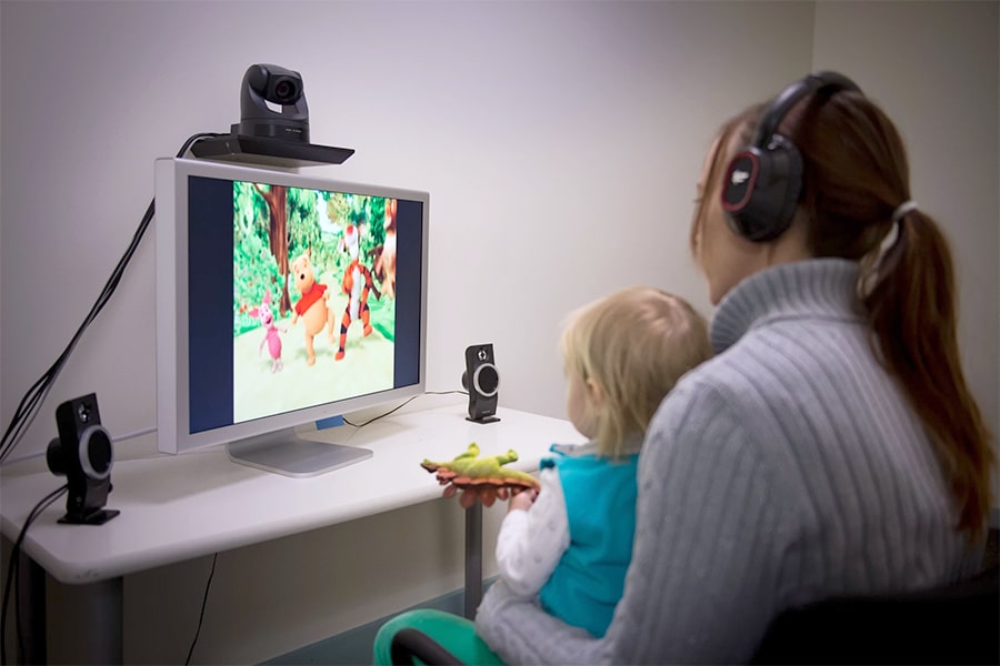 A child sits on their parent's lap while watching a screen in the Infant Lab