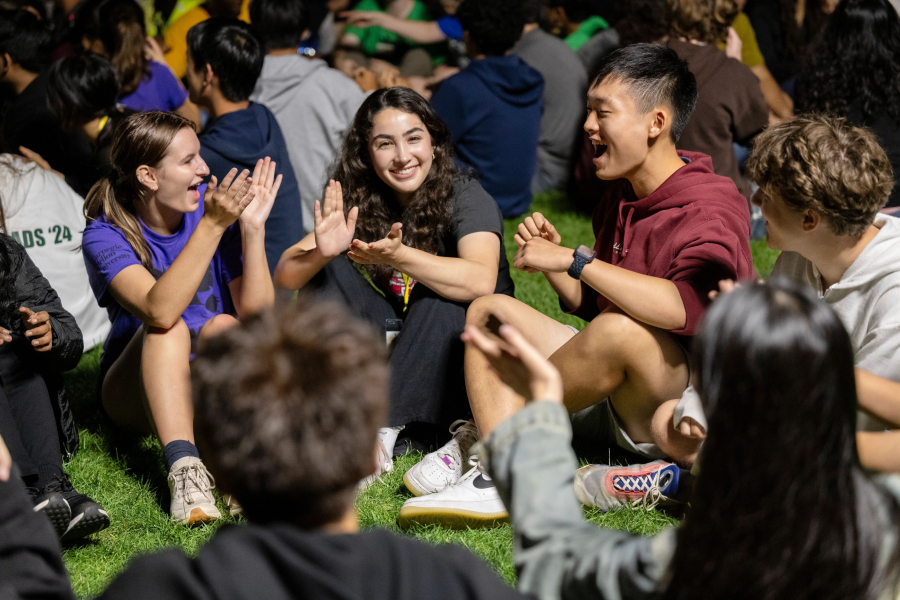 students sitting on the lawn clapping and smiling