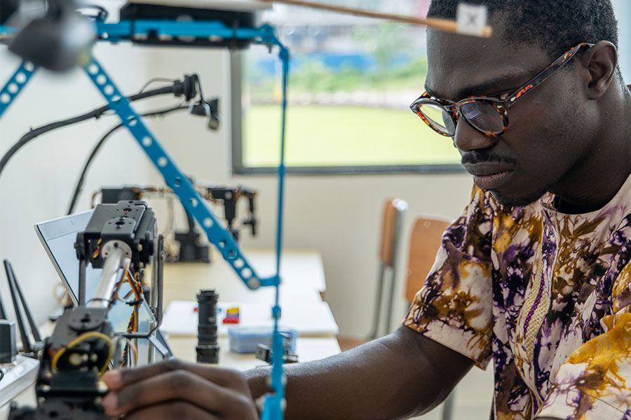Engineering student of Carnegie Mellon University in Africa, touching mechanical equipment.