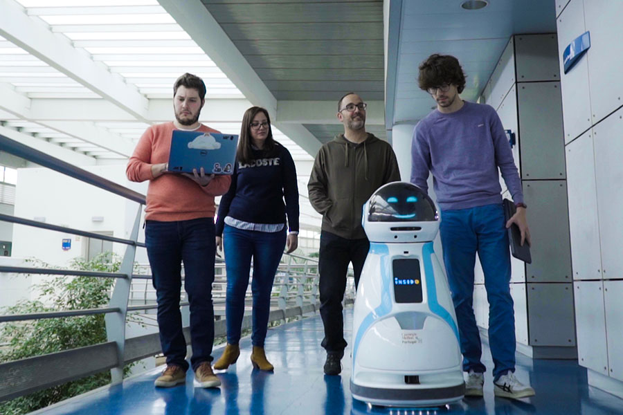 Students walking with a robot, monitoring data on a laptop, at Carnegie Mellon University Portugal.