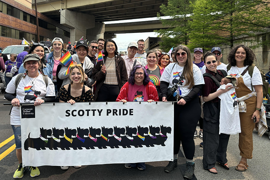 LGBTQIA+ Alliance members posing on parade route behind Scotty Pride banner