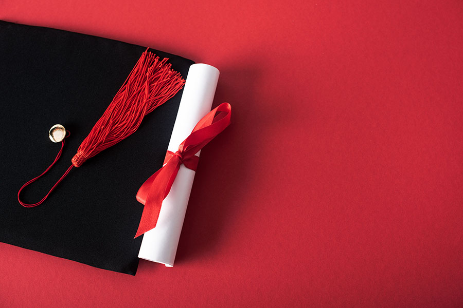 Certificate and mortarboard on red background