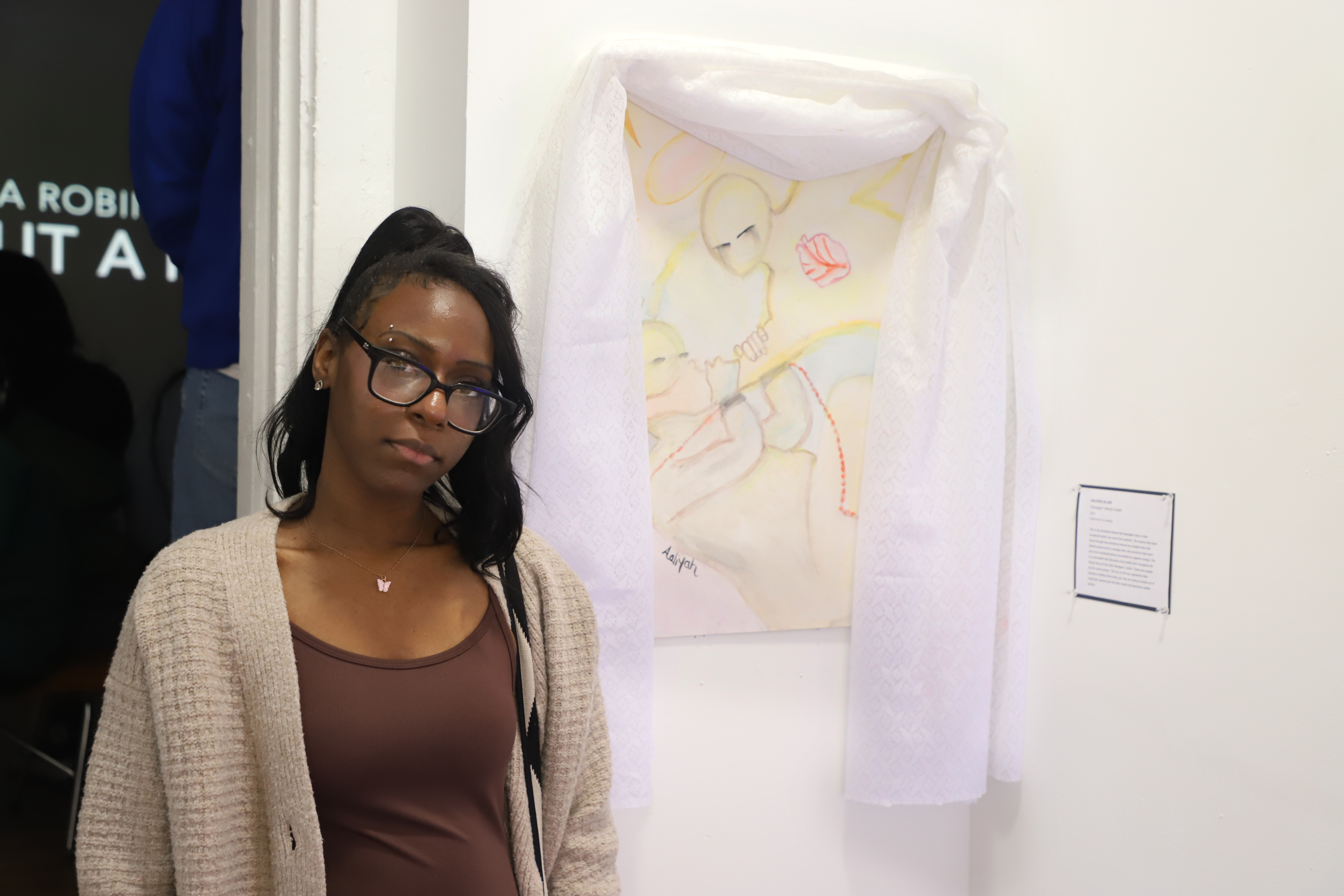 LEAP student Aaliyah standing next to a watercolor painting with a lace curtain draped over the top