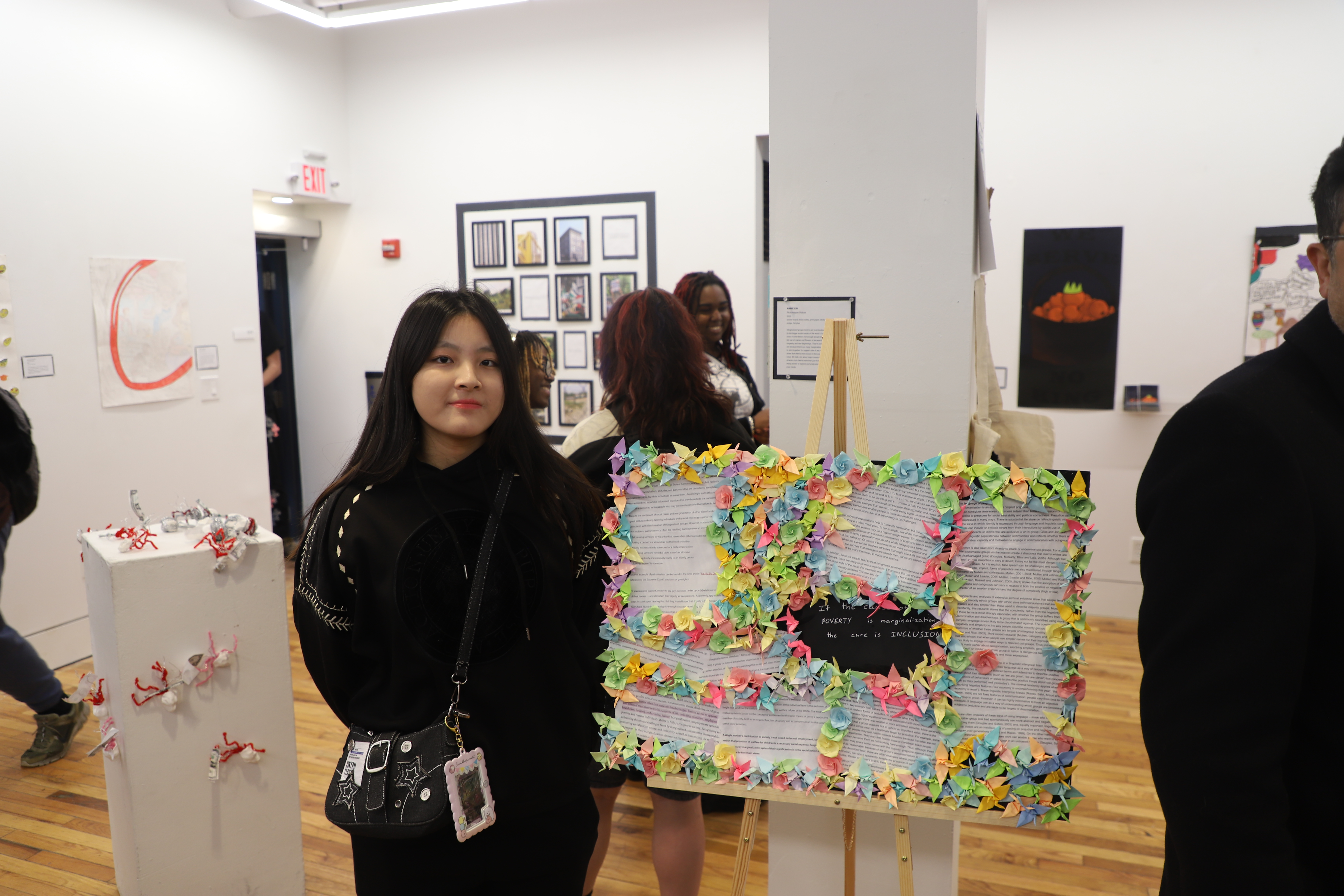 LEAP student Annie standing next to a board covered in words and origami