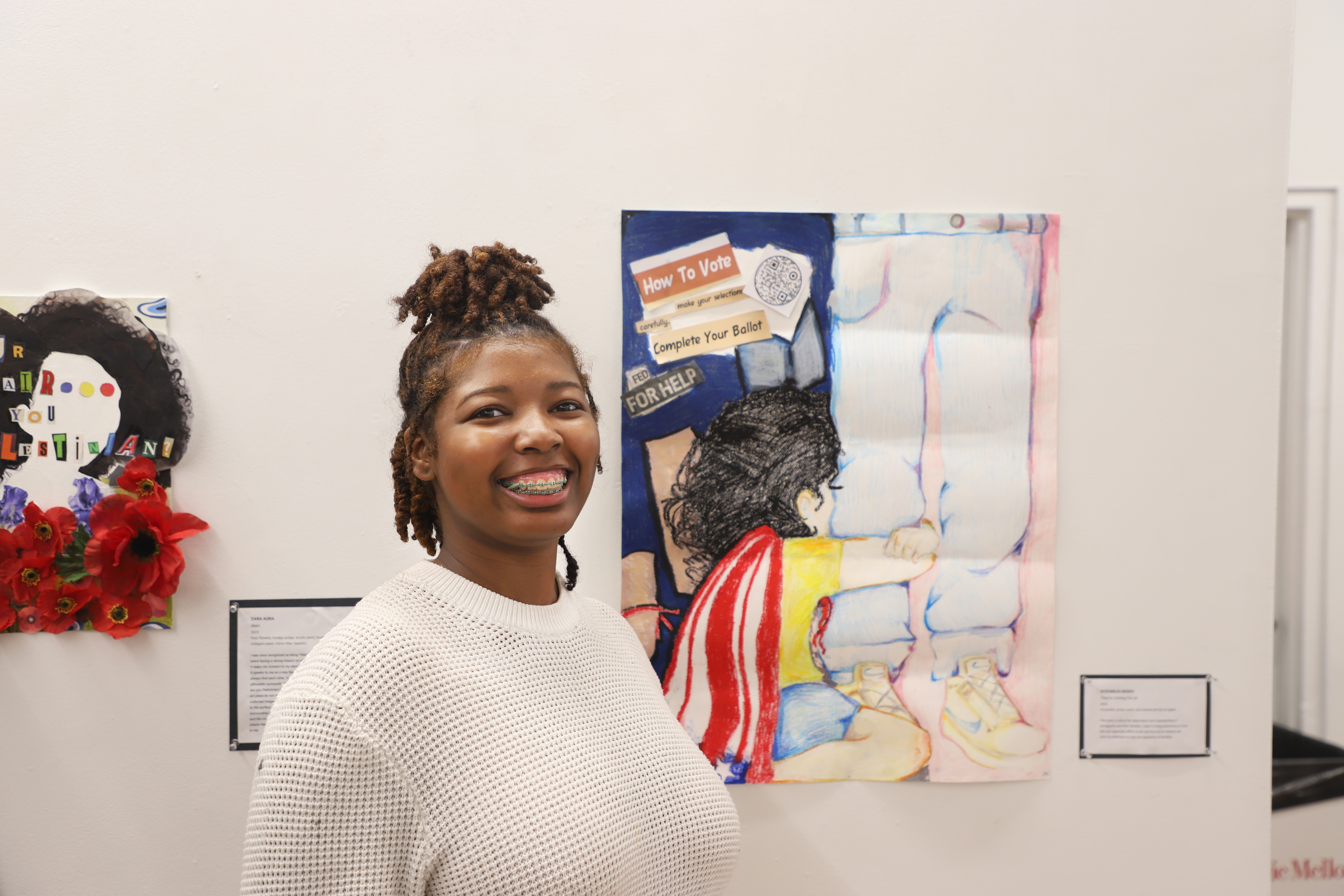 LEAP student Bleu standing next to a pastel drawing she created