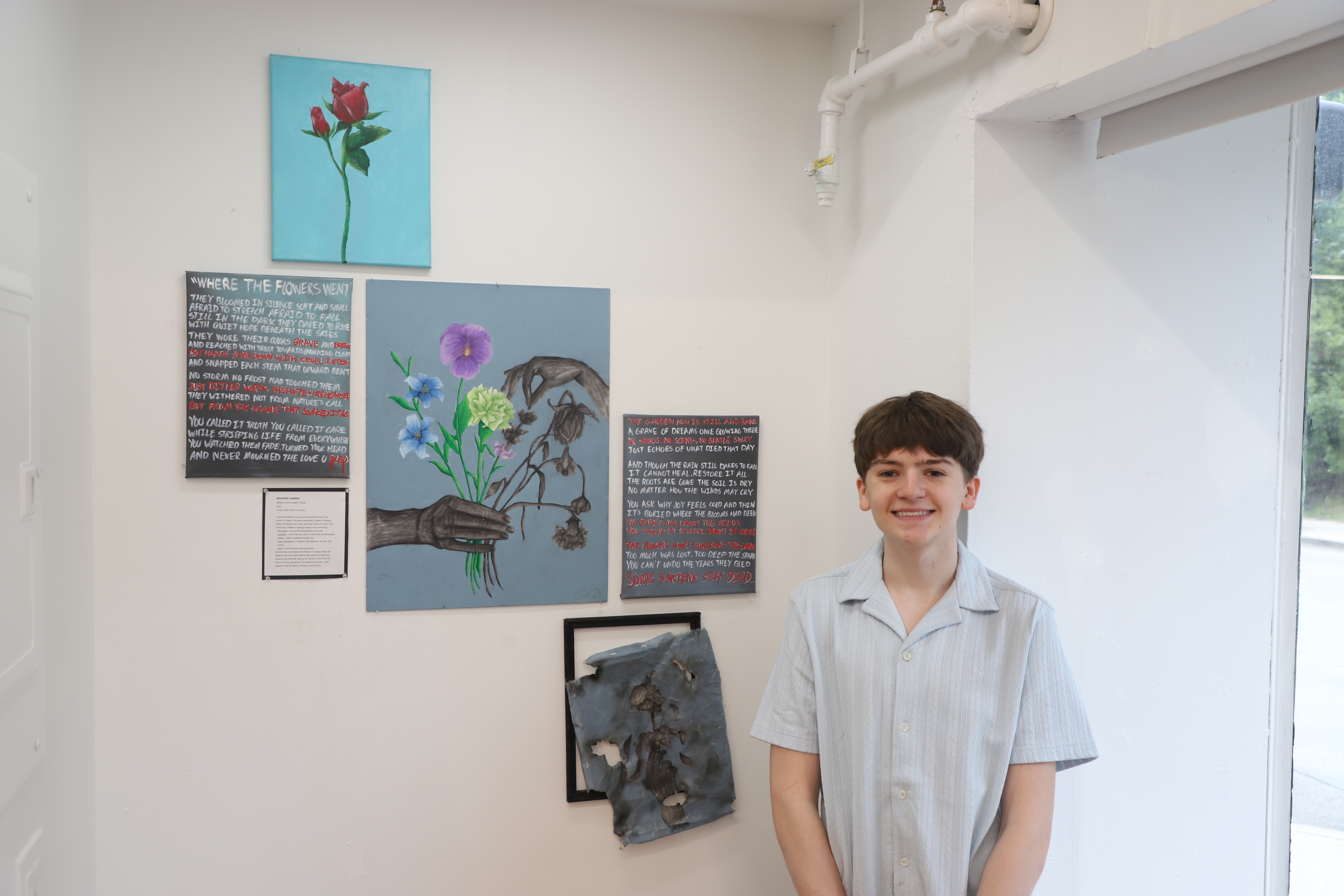 LEAP student Brayden next to a series of canvas paintings he created