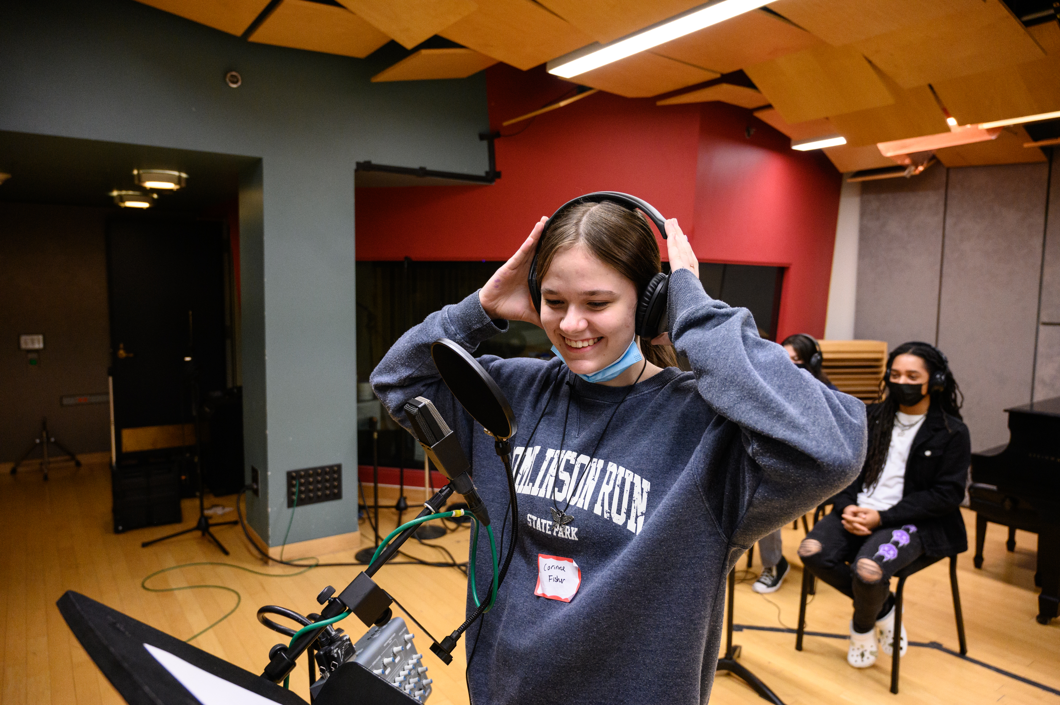 LEAP student smiling behind a microphone in the audio recording studio in CMU's College of Fine Arts