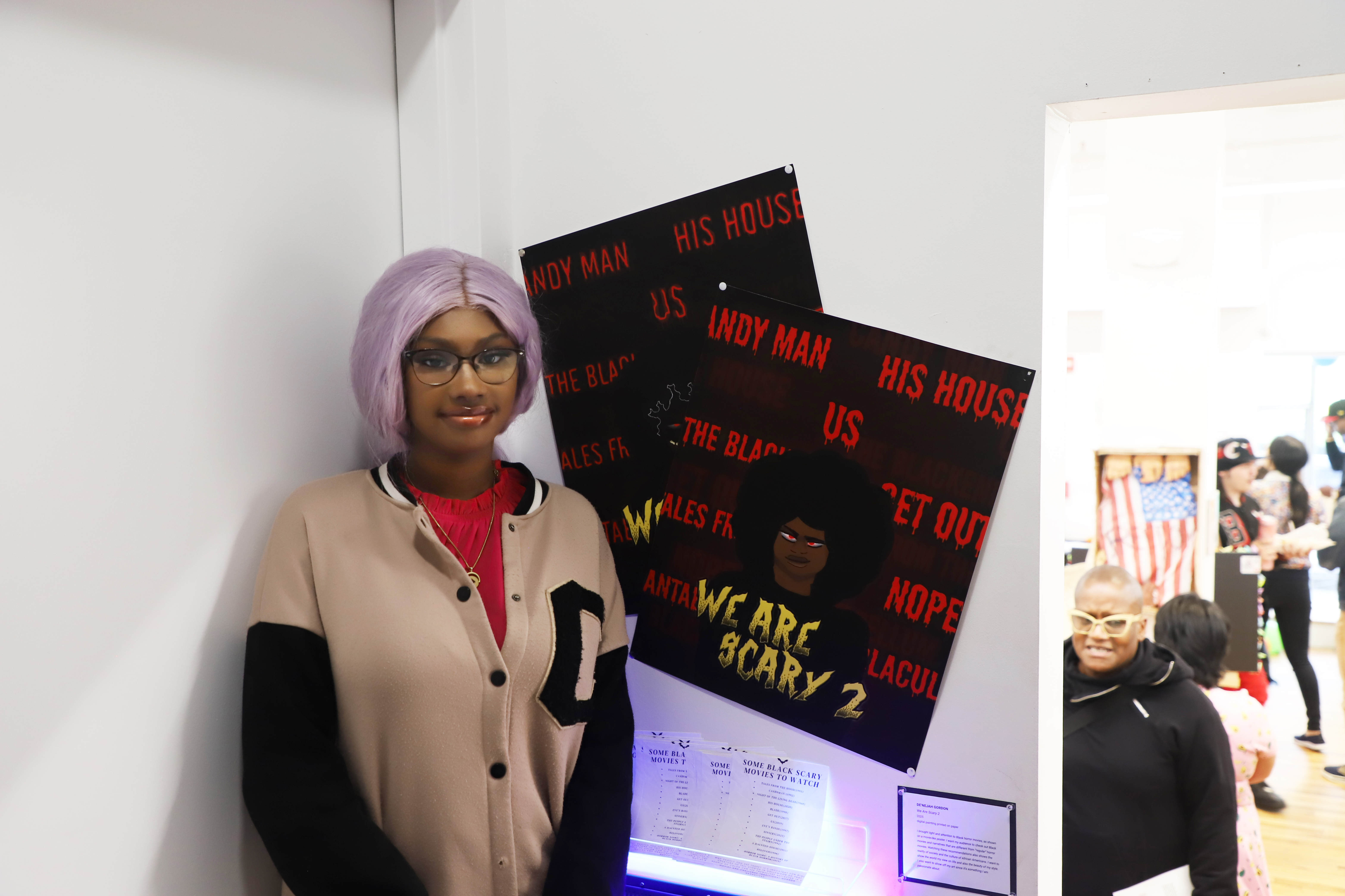 LEAP student De'Nejah standing next to the movie poster designs she created