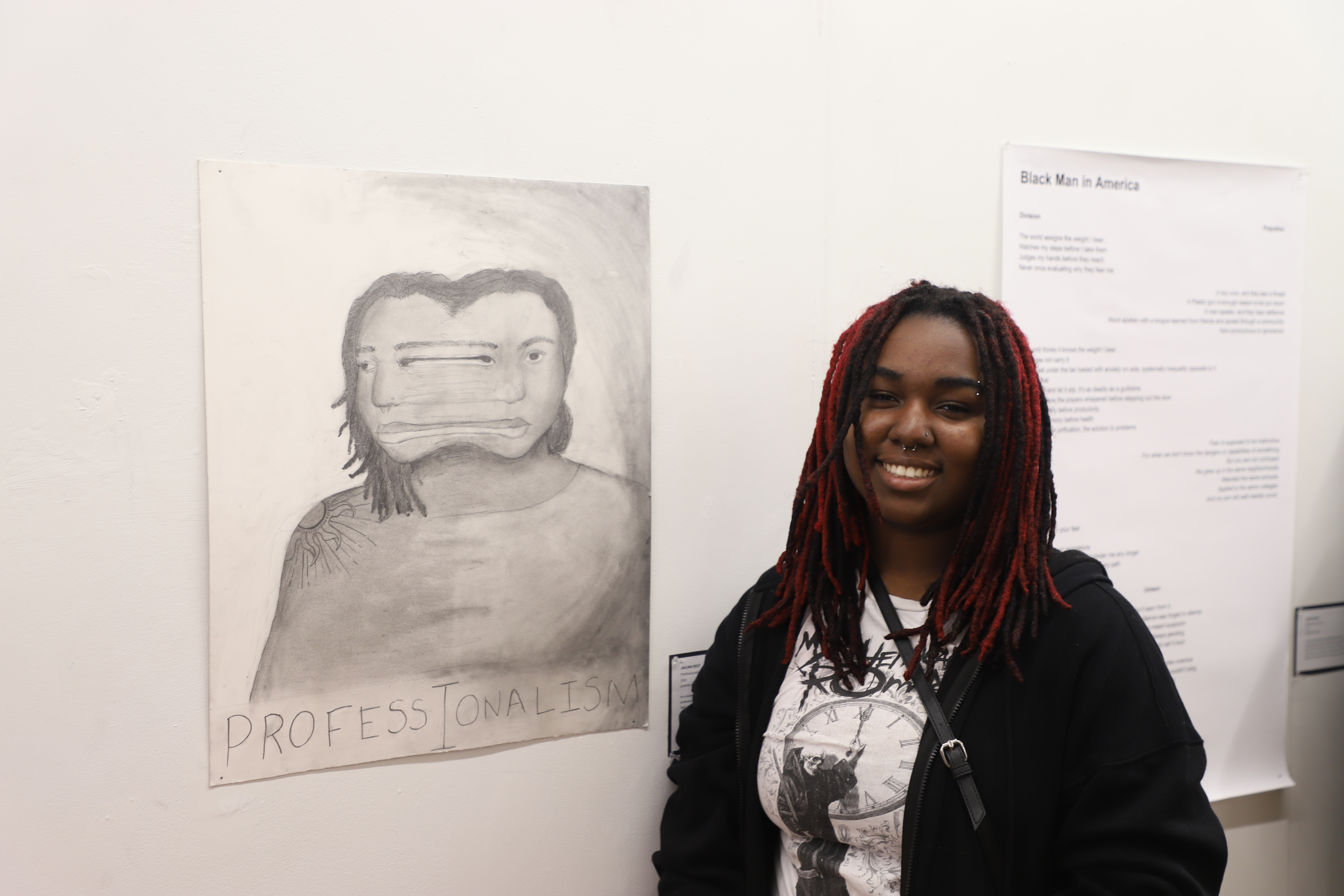LEAP student Jailinn standing next to a graphite drawing they created