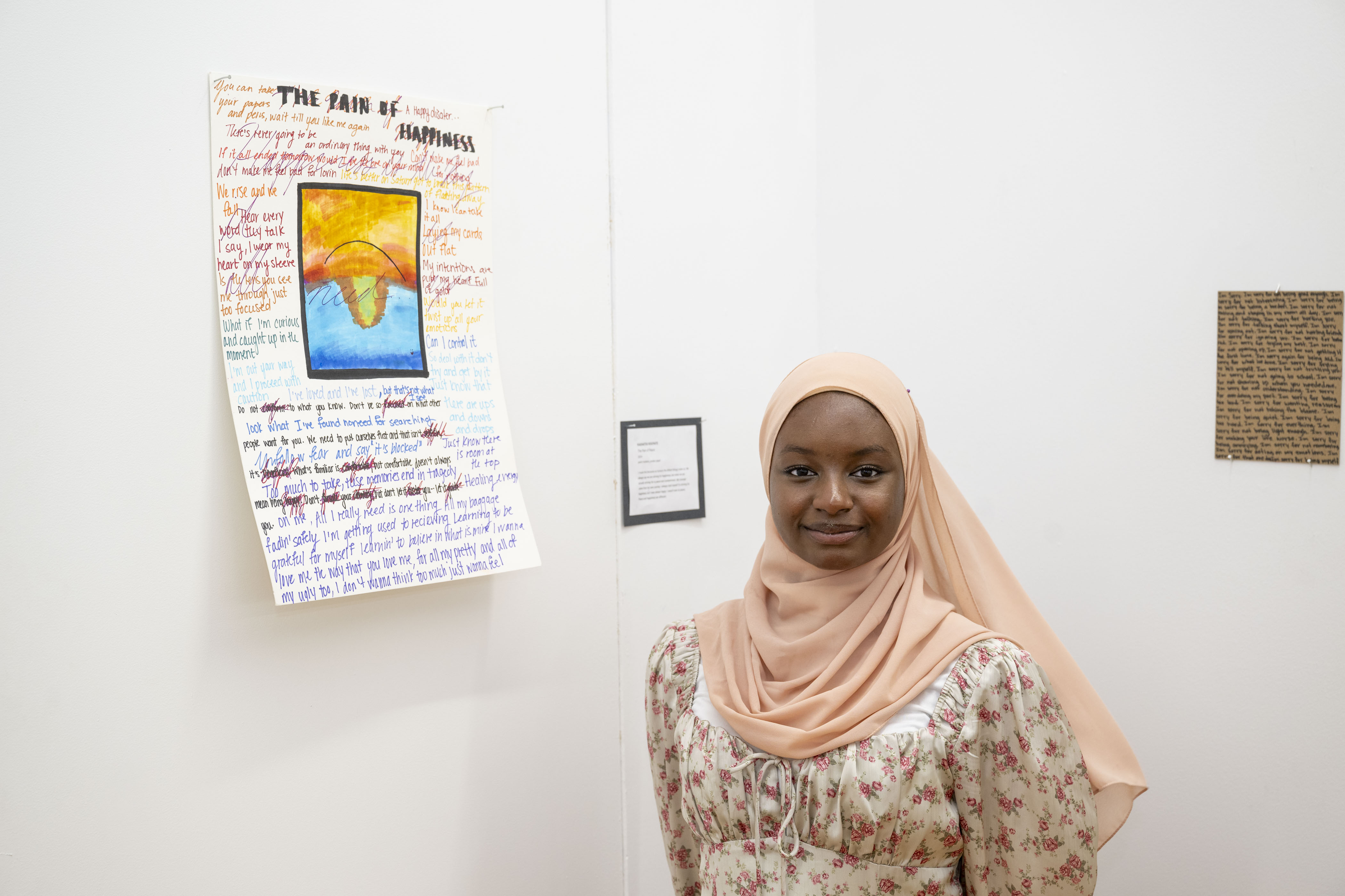 LEAP student Kadiatou K standing next to a poem and drawing she created