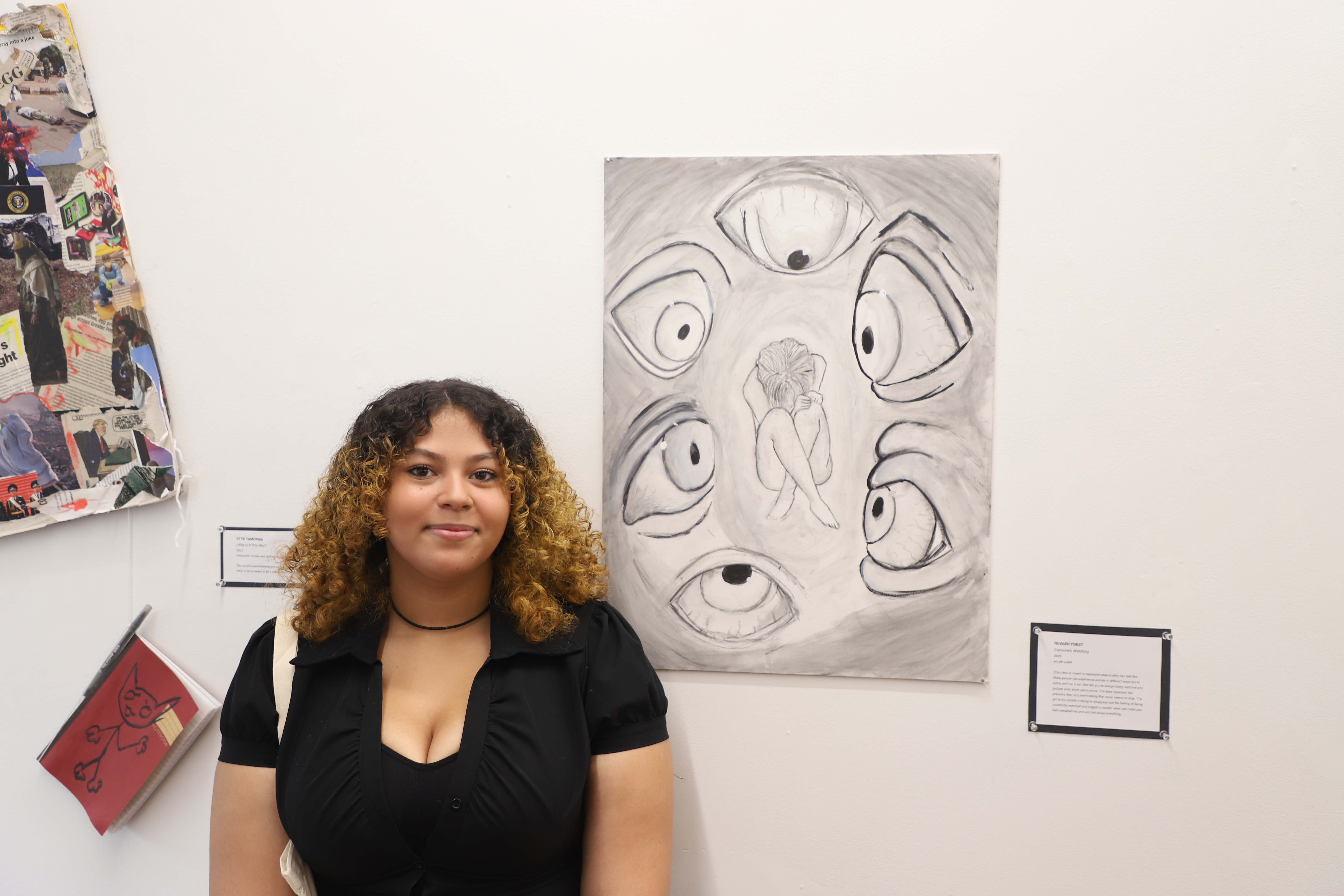 LEAP student Nevaeh holding his daughter and standing in front of a collage and drawing he created