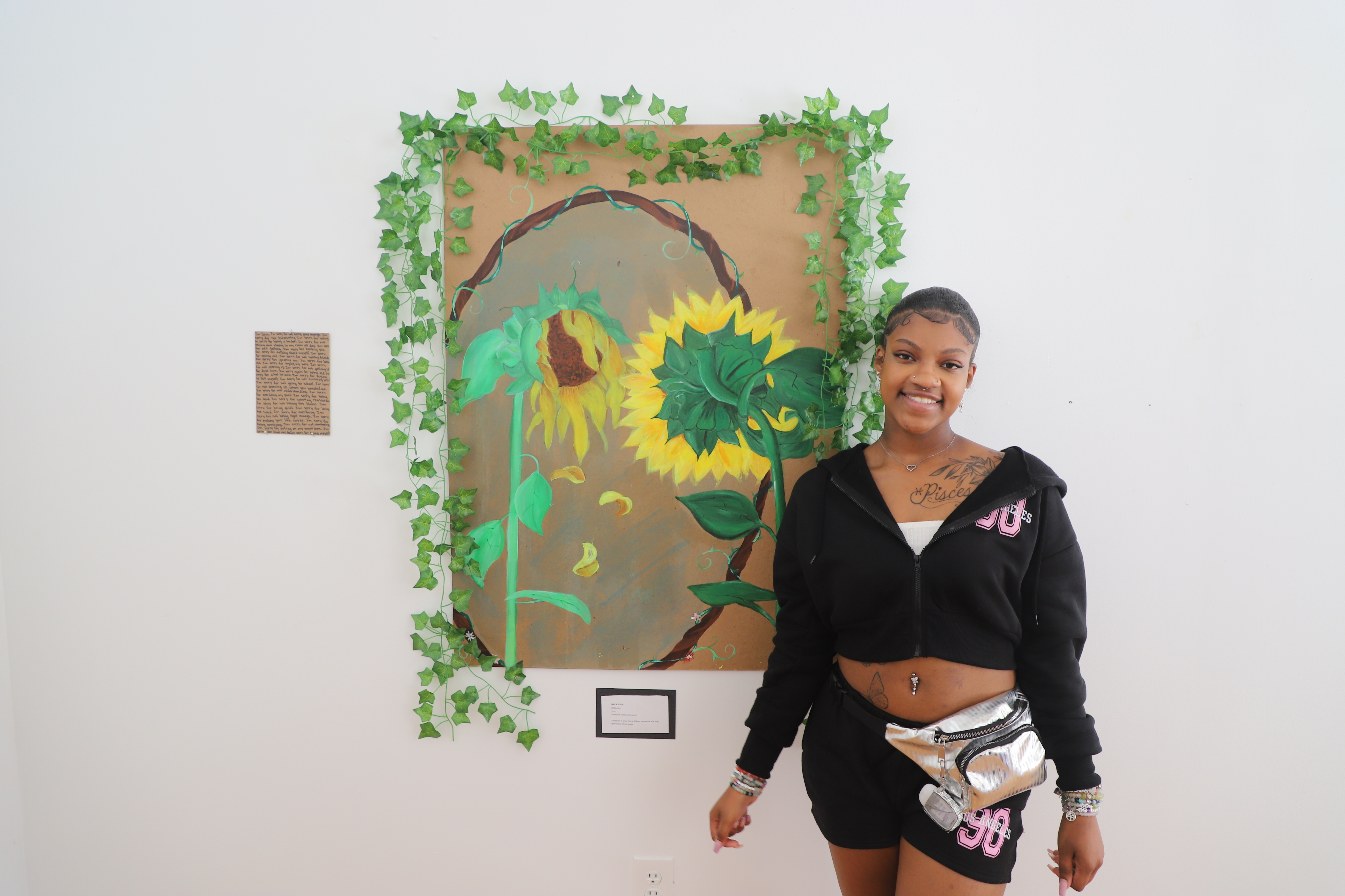 LEAP student, Nyla, standing in front of a large painted she created.