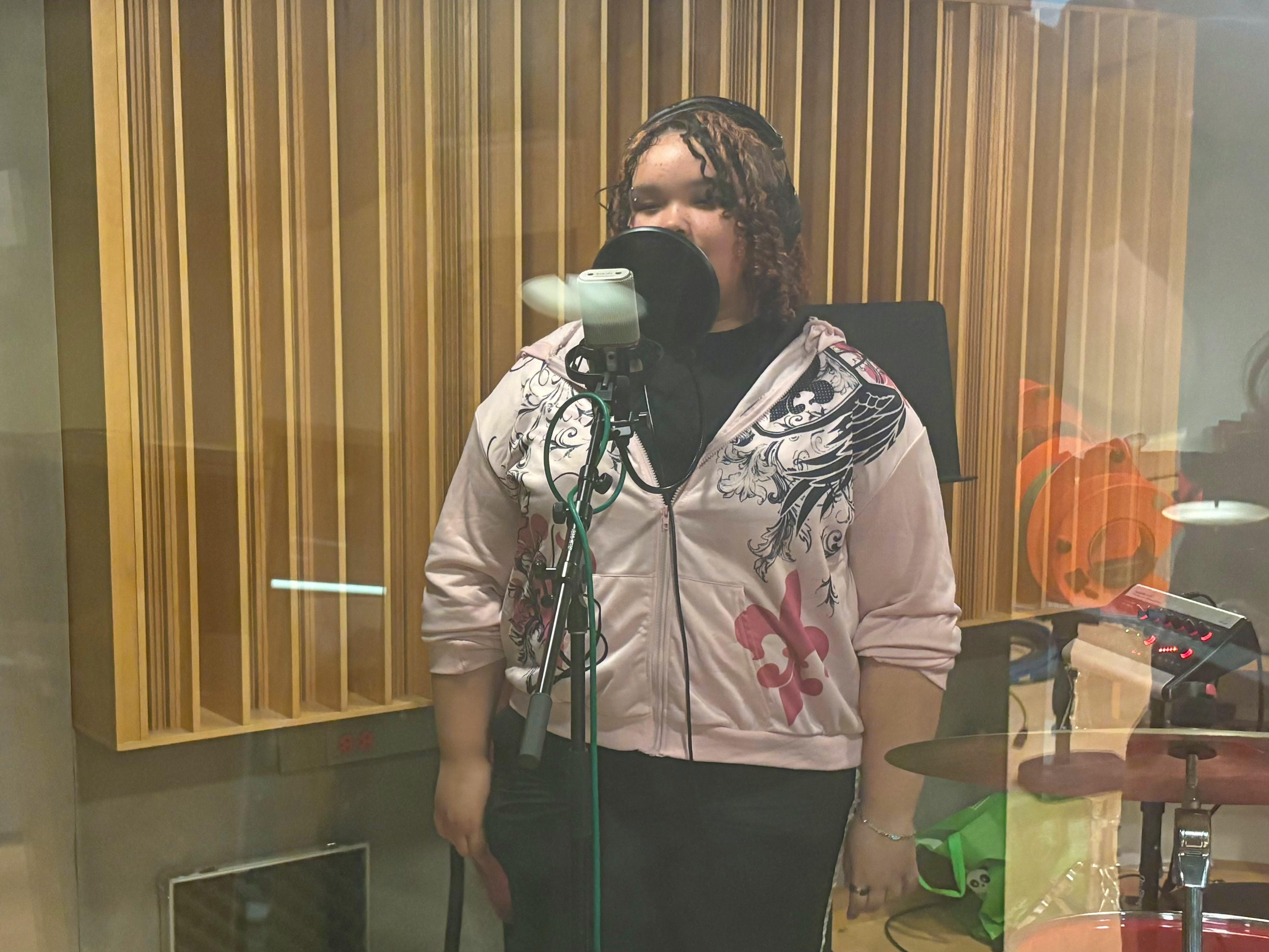 LEAP student Tameara recording a song in front of a microphone in the CMU recording studio