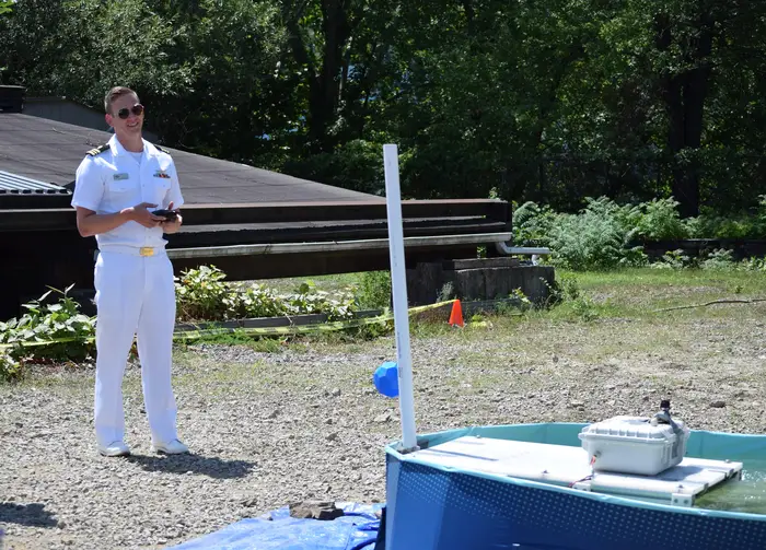 A sailor pilots a remote controlled robot in a tub of water