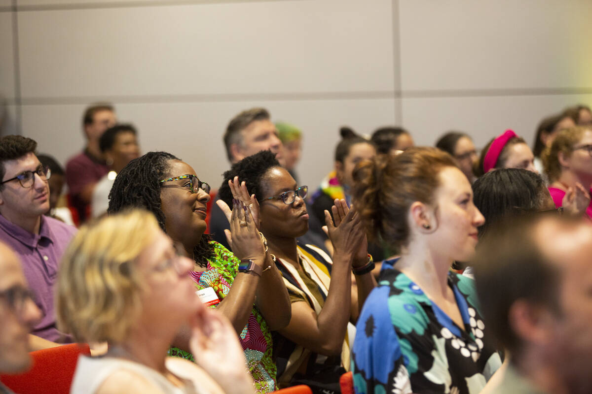 In a crowd of seated, applauding audience members who are mostly blurred out of focus, two Black women in the center of the photo applauding are in focus.