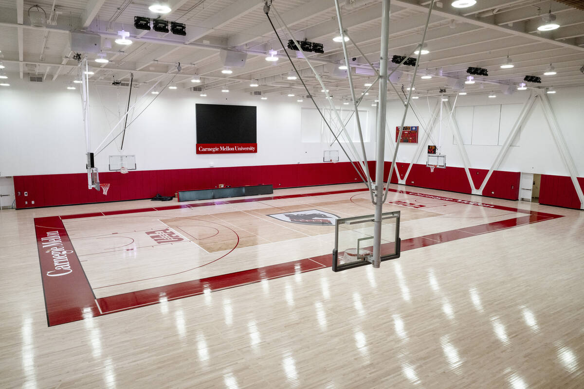 View from top of bleachers looking down in to basketball gymnasium with boundaries lined in red and lined with red padding on the walls. Blank scoreboard on the wall reads "Carnegie Mellon University" underneath.