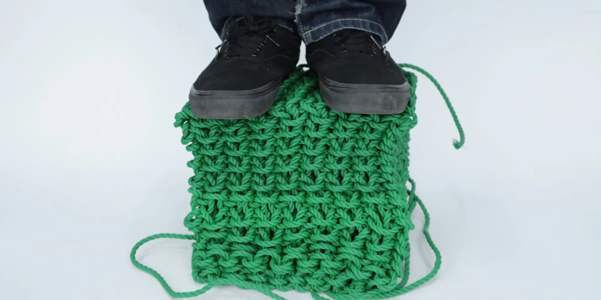 A person stands on a knitted cube made with a new fabrication technique.