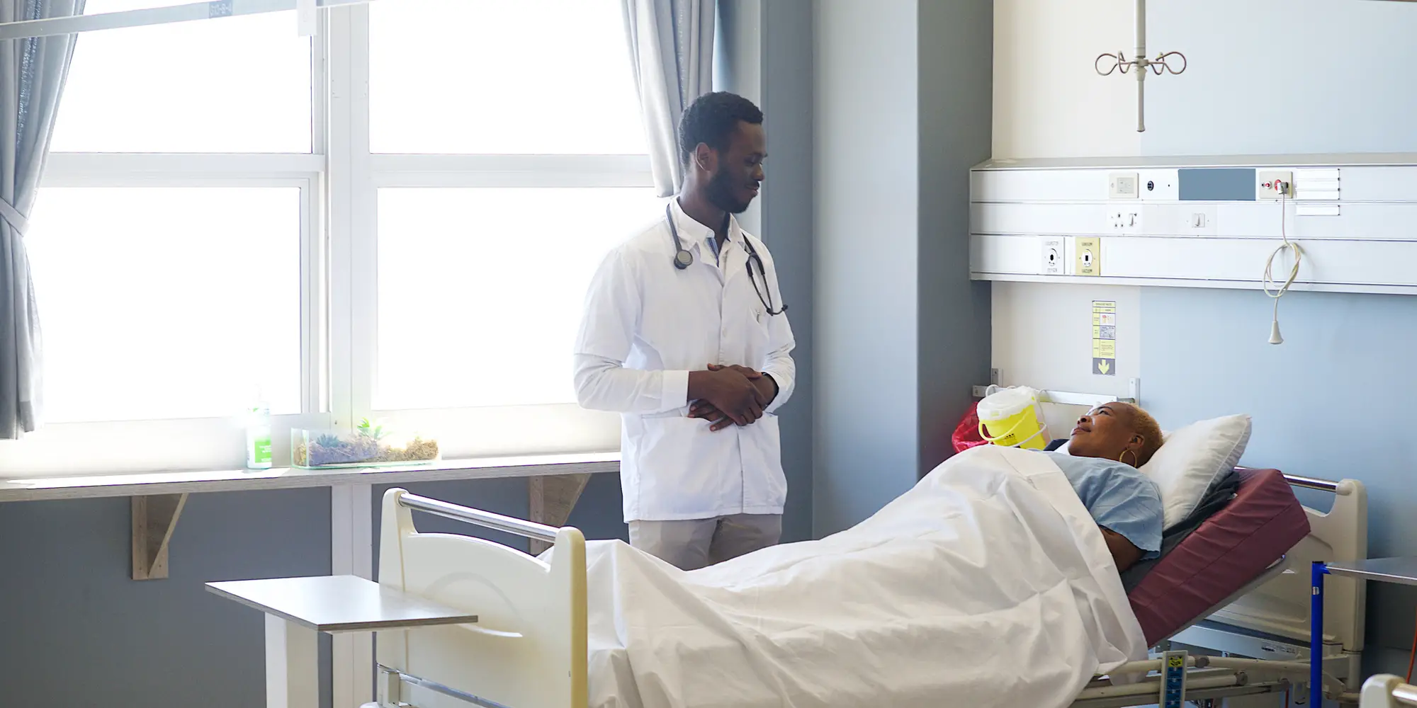 Black patient in a hospital bed, speaking to a doctor