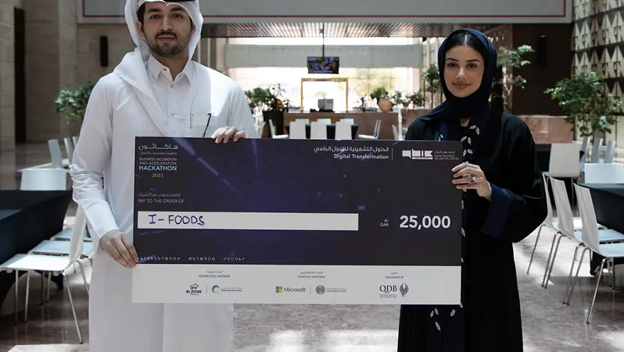 Two Qatar students holding large check