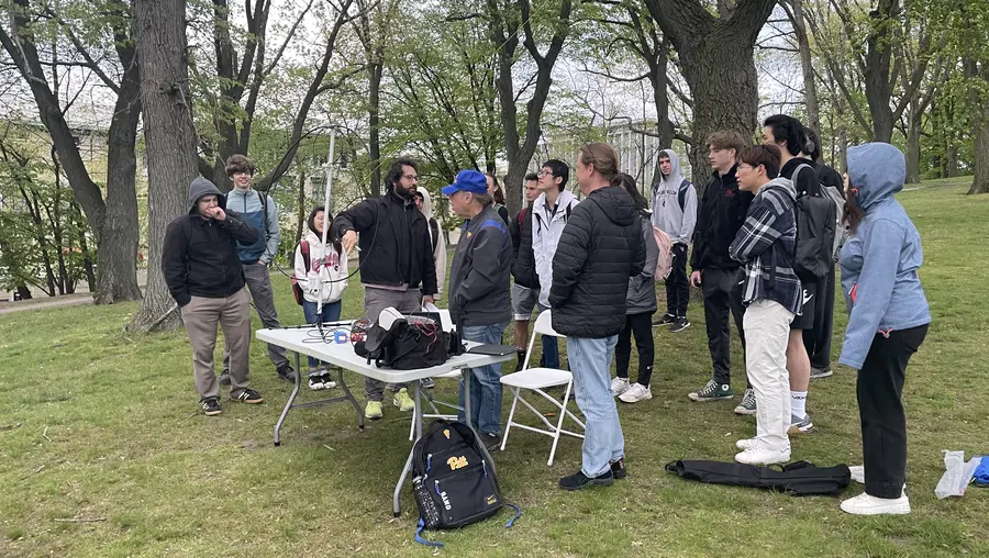 teacher instructing class outdoors under the trees