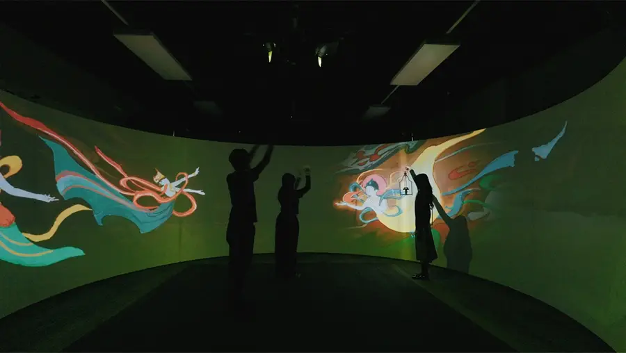 People in front of a large, colorful interactive screen. 