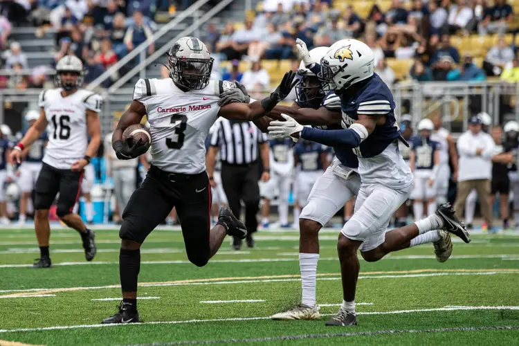 A running back in football pushes back against defenders.