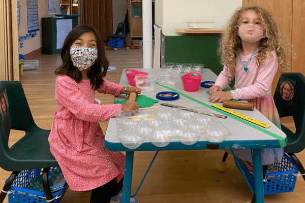 children wearing masks play with play dough