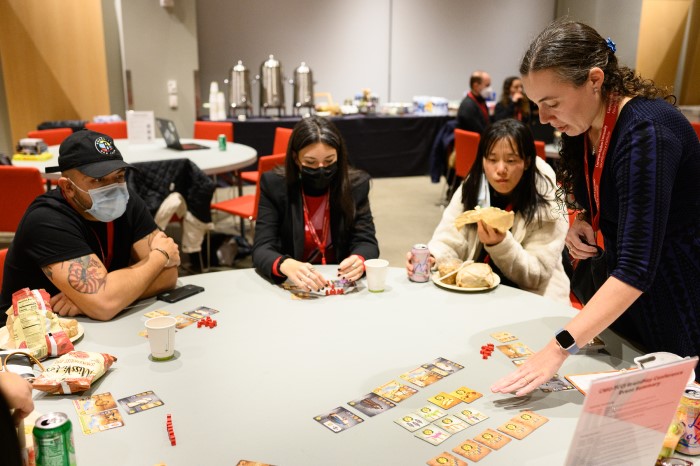 A picture of brainplay conference attendees sitting at a table playing a card game.