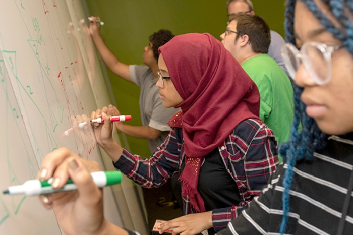 Pre-College CS Scholars students working on whiteboard.