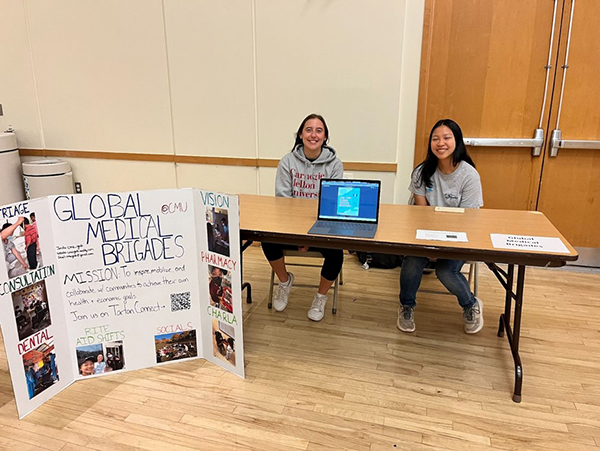 Images of two student leaders at the Global Medical Brigades table at the Study Abroad Fair