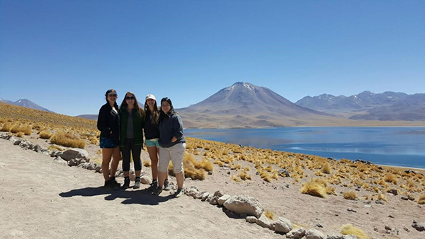 Images of four students standing in front a lake and mountain range