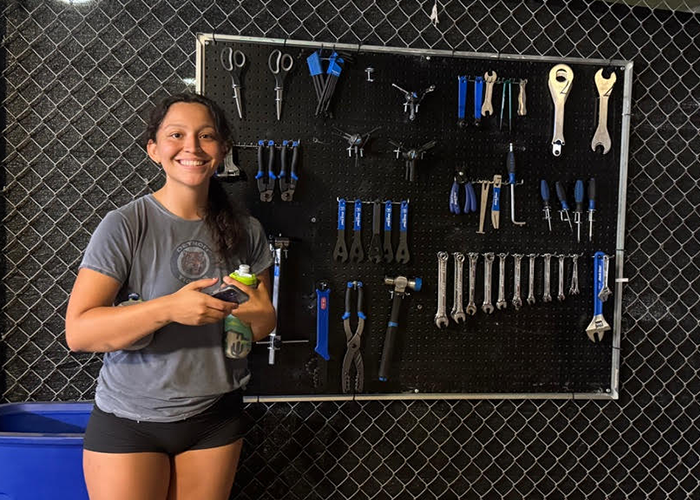 student standing in front of wall of bike tools