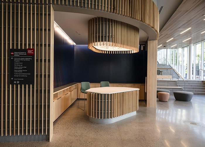 a concierge desk and stone stairway in a open and bright lobby