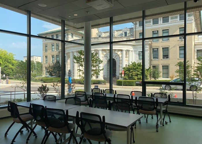 a large conference like table with chairs in a room with windows for walls