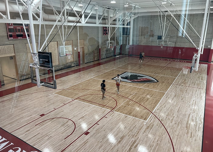 a big gymnasium with two students playing basketball